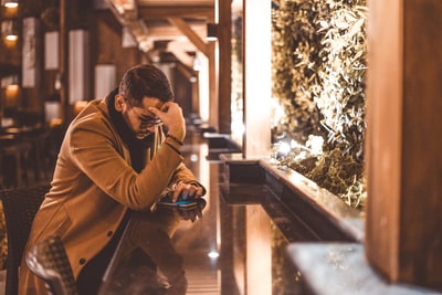 穿着棕色夹克的男人坐在棕色的木凳上